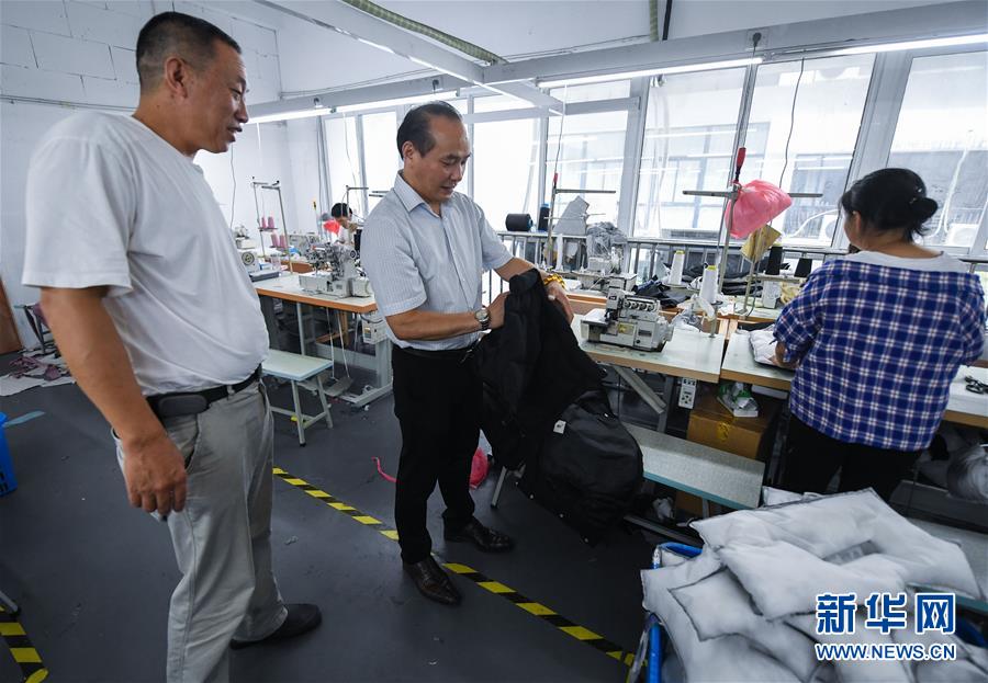 8月7日,织里镇的重庆商会会长胡毅(中)走访重庆籍企业家开办的童装